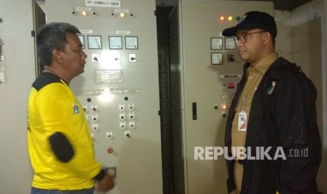 Gubernur DKI Jakarta Anies Baswedan saat meninjau panel listrik mesin pompa yang rusak ditemani Operator Pompa Mulyadi. 