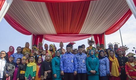 Gubernur DKI Jakarta Anies Baswedan (tengah) dan istri, Fery Farhati (kedelapan kiri) serta Wakil Gubernur DKI Jakarta Sandiaga Uno (ketujuh kanan) dan istri, Nur Asia (keenam kanan) berfoto bersama anak-anak dengan baju daerah saat hadir dalam peringatan Hari Sumpah Pemuda ke-89 di Lapangan IRTI Monas, Jakarta, Senin (30/10). 