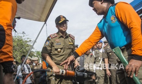 Gubernur DKI Jakarta Anies Baswedan (tengah) mendengan penjelasan anggota Satpol PP tentang fungsi alat mesin potong yang dipamerkan dalam Apel Besar Rotasi Satuan Polisi Pamong Praja (Satpol PP) DKI Jakarta di Monumen Nasional (Monas) , Jakarta, Jumat (29/12). 