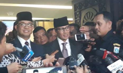 Gubernur DKI Jakarta Anies Rasyid Baswedan bersama mantan Wakil Gubernur DKI Jakarta Sandiaga Salahuddin Uno usai rapat paripurna DPRD DKI mengenai Pengumuman Pemberhentian Sandi sebagai Wakil Gubernur, Senin (27/8).