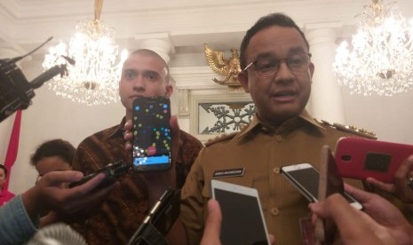 Gubernur DKI Jakarta Anies Rasyid Baswedan (kanan) dan Direktur PT Indonesia Lebih Aman Muhammad Fardhan (kiri) di Balai Kota, Jakarta Pusat, Selasa (12/3).