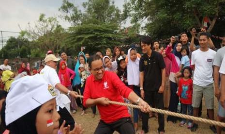 Gubernur DKI Jakarta Anies Rasyid Baswedan mengikuti perlombaan tarik tambang di lingkungan kediamannya di Jalan Lebak Bulus 1, Cilandak Barat, Jakarta Selatan, Jumat (17/8). Dia melakukan selebrasi usai menang pada permainan pertama.