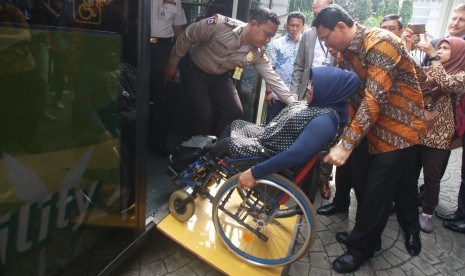 Gubernur DKI Jakarta Basuki Tjahaja Purnama (kanan) mendorong kursi roda penumpang disabilitas saat uji coba Scania Low Entry City Bus di Jakarta, Jumat (11/3).