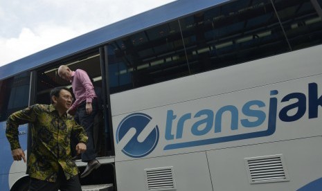 Gubernur DKI Jakarta Basuki Tjahaja Purnama (kiri) diikuti Duta Besar Australia untuk Indonesia Paul Grigson (kanan) turun dari bus Transjakarta saat meninjau kantor PT Transjakarta, Jakarta, Kamis (3/3).