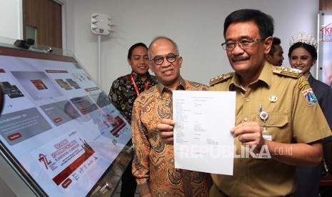 Gubernur DKI Jakarta Djarot Saiful Hidayat (kanan) melakukan transaksi pembayaran s