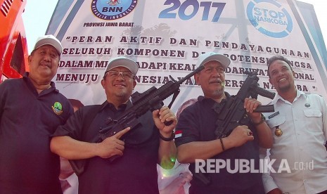 Gubernur Jabar Ahmad Heryawan dan Wakil Gubernur Deddy Mizwar memegang senapan sebagai simbol perang terhadap narkotika pada puncak Peringatan Hari Narkotika Internasional, di Komplek Gedung Sate, Kota Bandung, Senin (24/7).