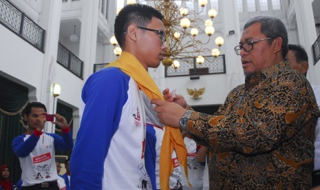 Gubernur Jabar Ahmad Heryawan (kanan) memasangkan syal ke perwakilan peserta saat pelepasan kontingen Jumpa Bakti Gembira Palang Merah Remaja (Jumbara PMR) VIII di aula Gedung Sate, Bandung, Jawa Barat, Jumat (22/7). 