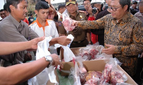 Gubernur Jabar Ahmad Heryawan membeli daging sapi saat meninjau operasi pasar daging sapi, di Pasar Kosambi, Kota Bandung, Rabu (12/8).  