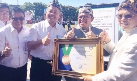 Gubernur Jabar Ahmad Heryawan (tengah), Wali Kota Sukabumi (kanan), dan Deputi Direksi BPJS Kesehatan Kedeputian Wilayah Jawa Barat Mohammad Edison (ketiga dari kanan) menunjukkan piagam deklarasi penetapan Universal Health Coverage (UHC) dalam peringatan Hari Jadi Kota Sukabumi ke-104 di Lapang Merdeka, Kota Sukabumi(1/04).      