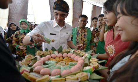 Gubernur Jambi Zumi Zola Zulkifli (tengah) memenuhi permintaan para pelajar untuk mencicipi aneka kue tradisional khas setempat produksi siswa-siswi SMK PGRI 2 Kota Jambi saat melakukan kunjungan ke sekolah tersebut di Jambi, Rabu (25/1).