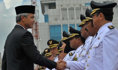 Gubernur Jateng Ganjar Pranowo (kiri) berjabat tangan dengan Wali Kota Solo FX. Hadi Rudyatmo pada pelantikan bupati dan wali kota yang terpilih dalam Pilkada serentak tahun 2015 di  Jateng, di Lapangan Pancasila Semarang, Rabu (17/2)