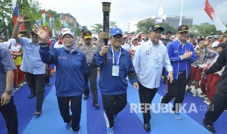 Gubernur Jawa Barat Ahmad Heryawan didamping istri Netty Heryawan bersama Wakil Gubernur Deddy Mizwar berlari membawa obor api di track lari saat Peresmian Track Lari Gasibu, di Lapangan Gasibu, Kota Bandung, Jumat (16/9). 