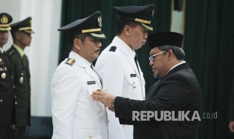 Gubernur Jawa Barat Ahmad Heryawan memasang tanda jabatan kepada Penjabat sementara (Pjs) Wali Kota Bekasi Rudi Gandakusumah dan Bupati Purwakarta Taufiq Budi Santoso, di Aula Barat, Gedung Sate, Kota Bandung, Selasa (13/3).