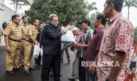 Gubernur Jawa Barat Ahmad Heryawan memberikan bantuan sosial (bansos) beras sejahtera (rastra) kepada warga di gedung Pakuan, Bandung, Jawa Barat, Senin (5/3). 