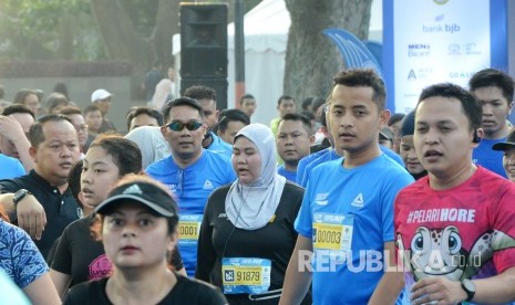 Gubernur Jawa Barat Ridwan Kamil (berkecamata) beserta peserta lain memasuki garis finis pada ajang Bandung West Java Marathon 2019, di depan Gedung Sate, Jalan Diponegoro, Kota Bandung, Ahad (28/7).