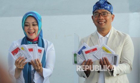 Gubernur Jawa Barat Ridwan Kamil berserta istrinya Atalia Praratya memperlihatkan surat suara usai melakukan pencoblosan Pemilu 2019, di TPS 32, Cigadung, Kota Bandung, Rabu (17/4).