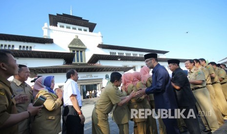 Gubernur Jawa Barat Ridwan Kamil berserta wakilnya Uu Ruzhanul Umum bersalaman dengan Aparatur Sipil Negara (ASN) pada hari pertama masuk kerja setelah libur Lebaran, di halaman Gedung Sate, Kota Bandung, Senin (10/6).