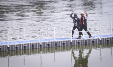 Gubernur Jawa Barat Ridwan Kamil (kanan) berjalan bersama Bonge (kiri) di atas floating brigde saat peresmian Situ Rawa Kalong di Curug, Depok, Jawa Barat, Jumat (5/8/2022). Usai Benahi Situ Rawa Kalong, Gubernur Ridwan Kamil ikut bantu membangun Depok.