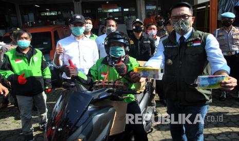 Gubernur Jawa Barat Ridwan Kamil (kanan) bersama Wakil Wali Kota Bogor Dedie A Rachim (kedua kiri) menunjukkan bantuan uang tunai saat pendistribusian bantuan Pemerintah Provinsi Jawa Barat di Gudang Kantor Pos, Kelurahan Cibadak, Tanah Sareal, Kota Bogor, Jawa Barat, Rabu (15/4/2020). Pemerintah Provinsi Jawa Barat mulai mendistribusikan bantuan bagi warga Kota Bogor yang terdampak secara ekonomi oleh pandemi Virus Corona (COVID-19). 