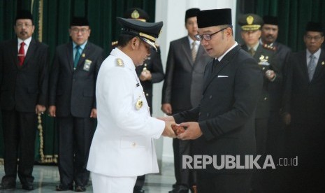 Gubernur Jawa Barat Ridwan Kamil (kanan) melantik Eka Supria Atmaja sebagai Bupati Bekasi definitif yang baru dilantik, di Aula Barat, Gedung Sate, Kota Bandung, Rabu (12/6).