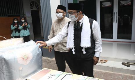 Gubernur Jawa Barat Ridwan Kamil (kanan) mengamati produk hasil dari program OPOP (One Pesantren One Product) di Pesantren PINK (Perguruan Islam Nurul Kasysyaf) 03, Tambun, Kabupaten Bekasi, Jawa Barat, Sabtu (16/4/2022). Program OPOP dari Pemprov Jawa Barat bagi pesantren yang ada di Kota/Kabupaten Bekasi tersebut dimaksudkan untuk mendorong dan menciptakan pesantren unggulan di bidang bisnis dan kemandirian ekonomi. 