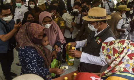 Gubernur Jawa Barat Ridwan Kamil (kedua kanan) mendistribusikan minyak goreng pada operasi pasar murah dengan harga Rp 14 ribu per liter.