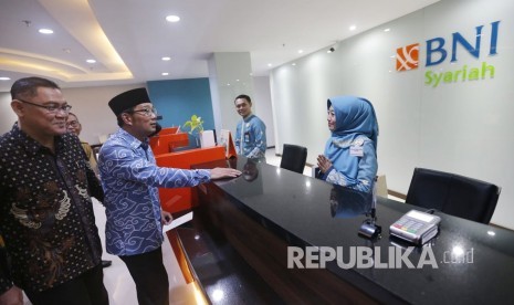 Gubernur Jabar Ridwan Kamil (kedua kiri) dan Direktur Utama PT Bank BNI Syariah Abdullah Firman Wibowo (kiri) meninjau pelayanan usai meresmikan Relokasi BNi Syariah Kantor Wilayah dan Cabang Bandung, di Jalan Asia Afrika, Kota Bandung, Selasa (13/11).