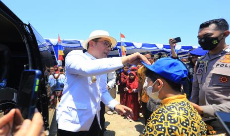 Gubernur Jawa Barat Ridwan Kamil (kiri) memasangkan topi kepada seorang anak saat bakti sosial di Kampung nelayan Karangsong, Indramayu, Jawa Barat, Kamis (15/9/2022). Polda Jabar bersama Pemprov Jawa Barat memberikan paket bantuan sembako kepada 2.000 nelayan di wilayah pesisir Pantura yang terdampak kenaikan harga BBM subsidi. 