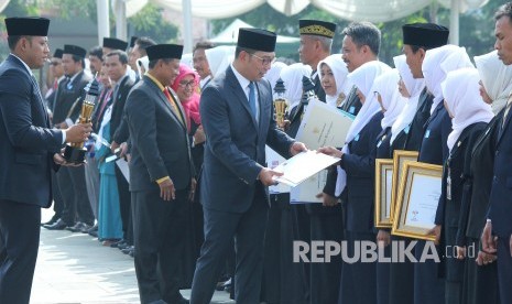 Gubernur Jawa Barat Ridwan Kamil memberikan penghargaan kepada sejumlah guru berprestasi saat upacara Peringatan Hari Guru Nasional Tingkat Provinsi Jawa Barat, di lapangan Gasibu, Kota Bandung, Senin (25/11).