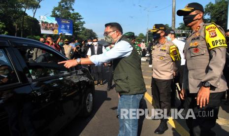 Gubernur Jawa Barat Ridwan Kamil (tengah) bersama Kapolda Jabar Irjen Pol Rudy Sufahriadi (kanan) berbincang dengan pengendara mobil saat pemantauan pelaksanaan Pembatasan Sosial Berskala Besar (PSBB) hari pertama di pos check point pintu keluar Tol Jagorawi, Kota Bogor, Jawa Barat, Rabu (15/4/2020). Gubernur Jawa Barat menilai pelaksanaan PSBB di Kota Bogor berjalan baik terlihat dari penurunan jumlah kendaraan yang masuk Kota Bogor lewat pintu Tol Jagorawi mencapai 50 persen.