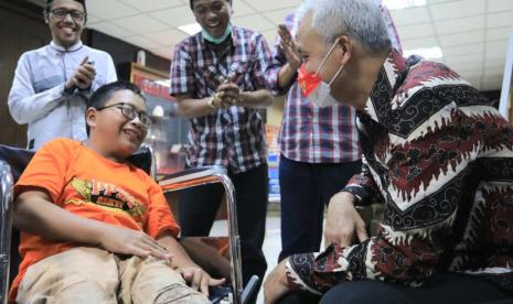 Gubernur Jawa Tengah, Ganjar Pranowo berdialog dengan Kholilur Rohman (12) bocah penyandang disabilitas asal Desa Gunungpring, Kecamatan Muntilan, Kabupaten Magelang sebelum memberikan bantuan kursi roda elektrik, di kantor Gubernuran, Smarang, Senin (3/10).