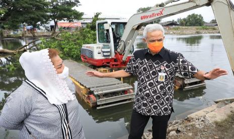 Gubernur Jawa Tengah, Ganjar Pranowo berdiskusi dengan Wakil Wali Kota Semarang, Hevearita Gunaryanti Rahayu, saat memantau pengerukan sedimentasi sungai di Pasar Waru, Kecamatan Gayamsari, Kota Semarang, Rabu (10/2). Upaya untuk menagani problem banjir di sejumlah wilayah Kota Semarang yang belum surut terus dikebut.