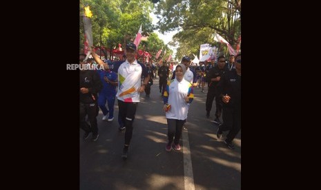 Gubernur Jawa Tengah Ganjar Pranowo dan Istri ikut partai menjadi pembawa obor Asian Games dalam Torch Relay Asian Games di Solo Jawa Tengah, Kamis (19/7). 