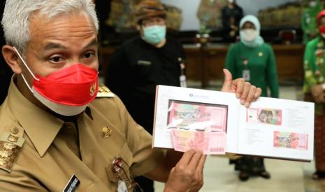 Gubernur Jawa Tengah, Ganjar Pranowo membandingkan uang pecahan Rp 100.000 tahun emisi 2022 dengan uang pecahan yang sama tahun emisi 2016, dikantor gubernuran, Semarang, Kamis (18/9).