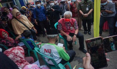 Gubernur Jawa Tengah Ganjar Pranowo (tengah) berbincang dengan warga penerima bantuan di Wonopringgo, Kabupaten Pekalongan, Jawa Tengah, Selasa (19/4/2022). Dalam kunjungan itu, Gubernur Jawa Tengah memastikan bantuan langsung tunai (BLT) minyak goreng dapat disalurkan dengan baik kepada warga penerima manfaat dan mengapresiasi diadakannya vaksin booster di lokasi sebelum warga menerima bantuan.