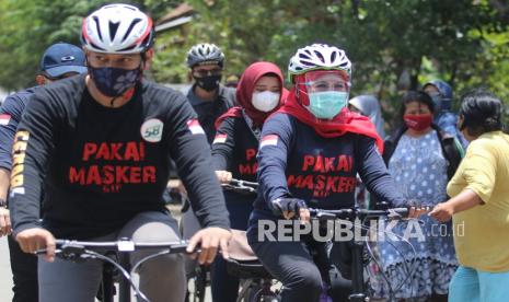 Gubernur Jawa Timur Khofifah Indar Parawansa (kanan) didampingi Wali Kota Kediri Abdullah Abu Bakar (kiri) mengayuh sepeda di Kota Kediri, Jawa Timur, Sabtu (3/10/2020). Bersepeda saat kunjungan kerja tersebut dilakukan Gubernur Jatim untuk mensosialisasikan penggunaan masker di tengah masyarakat guna memutus mata rantai penyebaran COVID-19.