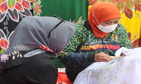 Gubernur Jawa Timur Khofifah Indar Parawansa (kanan) membatik di stand pameran UMKM usai mengikuti gowes bersama komunitas di Jember, Jawa Timur, Sabtu (18/6/2022). Gubernur Jawa Timur mengikuti gowes bersama komunitas usai melepas acara Super Road Bike dalam rangkaian Pekan Olahraga Provinsi (Porprov) VII Jawa Timur 2022. 