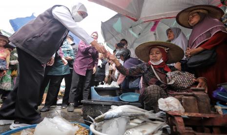 Gubernur Jawa Timur Khofifah Indar Parawansa (kiri) membeli ikan dari pedagang saat membagikan bantuan usaha ultra mikro berupa zakat produktif di Pasar Ikan Lamongan, Lamongan, Jawa Timur, Selasa (20/9/2022). Zakat produktif senilai Rp500 ribu per pedagang tersebut diperuntukkan bagi pelaku usaha ultra mikro guna memberikan penguatan bantalan sosial untuk pengendalian angka inflasi di daerah. 