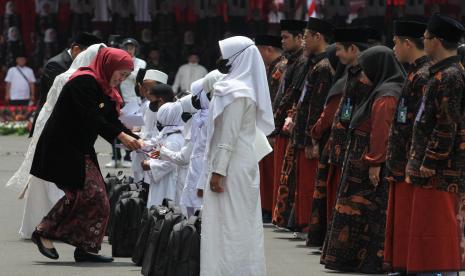 Gubernur Jawa Timur Khofifah Indar Parawansa (kiri) memberikan santunan kepada sejumlah anak saat upacara peringatan Hari Santri Nasional di Gedung Negara Grahadi, Surabaya, Jawa Timur, Sabtu (22/10/2022). Upacara tersebut bertema Berdaya Menjaga Martabat Kemanusiaan.