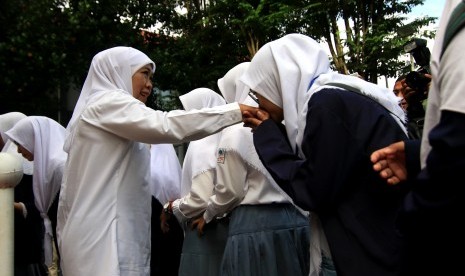 Gubernur Jawa Timur Khofifah Indar Parawansa (Kiri) menyalami siswa peserta Ujian Nasional Berbasis Komputer (UNBK) di SMKN 1 Giri, Banyuwangi, Jawa Timur, Senin (25/3/2019).