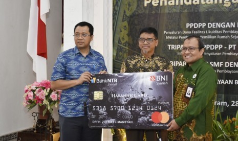 Gubernur Nusa Tenggara Barat, Zulkieflimansyah (kiri) turut menyaksikan simbolis penyerahan mock up Hasanah NTB Syariah Card yang diterima langsung oleh Direktur Utama Bank NTB Syariah, Kukuh Rahardjo (tengah) dari Direktur Keuangan dan Operasional BNI Syariah, Wahyu Avianto (kanan) di Pendopo Kantor Gubenur NTB, Mataram. Kamis (28/2).