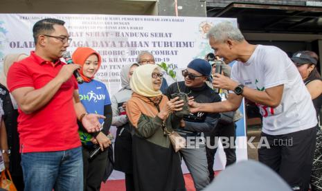 Gubernur Provinsi Jawa Barat Ridwan Kamil (kiri) bersama Gubernur Provinsi Jawa Tengah Ganjar Pranowo (kanan) memberikan bibit tanaman kepada warga saat acara Gerakan Jawa Barat Sehat di Kawasan hari bebas kendaraan Dago, Bandung, Jawa Barat, Minggu (8/3/2020).