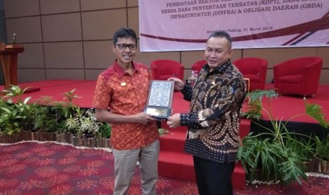 Gubernur Sumbar menerima plakat dari OJK usai memberikan pidato di seminar Pembiayaan sektor riil dan infrastruktur Melalui RDPT, Dinfra dan Oblgasi Daerah' di Hotel Grand Inna Padang, Kamis (21/3).