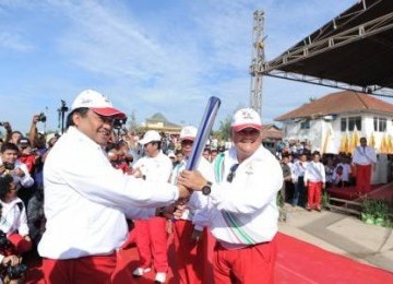 Gubernur Sumsel Alex Noerdin (kanan) menerima Obor Api SEA Games dari Ketua INASOC Rahmat Gobel (kiri) di Dermaga Pelabuhan Boom Baru Palembang, Sumsel, Senin (7/11).