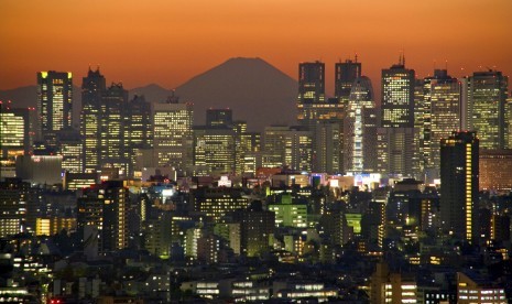 Gunung Fuji menjadi latar pemandangan saat senja di tengah belantara gedung pencakar langit Shinjuku di Tokyo, Jepang.