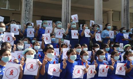 Guru dari Universitas Pendidikan Yangon menunjukkan gerakan protes tiga jari sambil memegang papan nama di Yangon, Myanmar Jumat, 5 Februari 2021. Seorang anggota senior partai berkuasa Myanmar yang digulingkan menjadi politisi terkemuka terbaru yang ditangkap saat pemerintah militer baru negara itu berhadapan. melanjutkan perlawanan terhadap perebutan kekuasaannya. Rambu-rambu bertuliskan Pembangkangan Sipil Guru Myanmar.