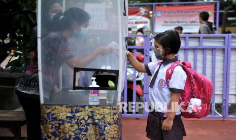 Guru memeriksa suhu tubuh siswa sebelum memasuki kelas saat simulasi pembelajaran tatap muka. ilustrasi