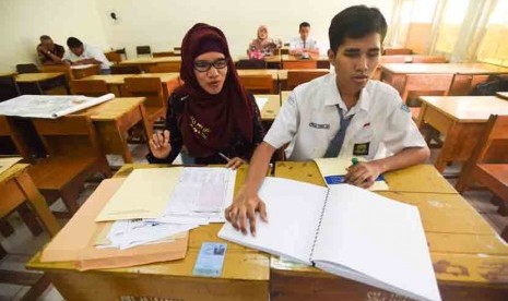 Guru mendampingi siswa berkebutuhan khusus mengikuti ujian nasional paper based test (Pbt) di SMAN 10 Surabaya, Jawa Timur, Senin (13/4). ANTARA/Zabur Karur