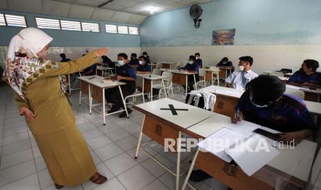 Guru mengajar muridnya di ruang kelas di SMK Negeri 7 Surabaya, Jawa Timur, Senin (30/8). Pemprov Jawa Timur memulai pembelajaran tatap muka (PTM) secara terbatas di 2.536 SMA/SMK dan SLB di 20 kabupaten/kota di Jawa Timur yang telah menerapkan PPKM Level 2 dan 3, sedangkan di wilayah PPKM level 4 kegiatan PTM secara terbatas belum digelar. 