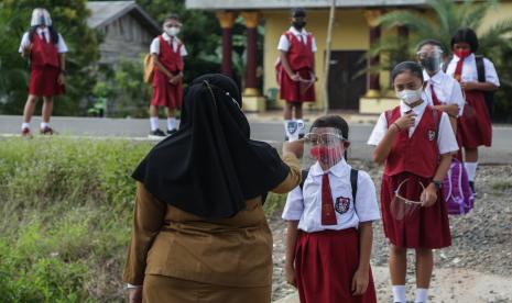 Guru mengukur suhu tubuh siswa SD sebelum melakukan pembelajaran tatap muka terbatas (PTMT). Ilustrasi.